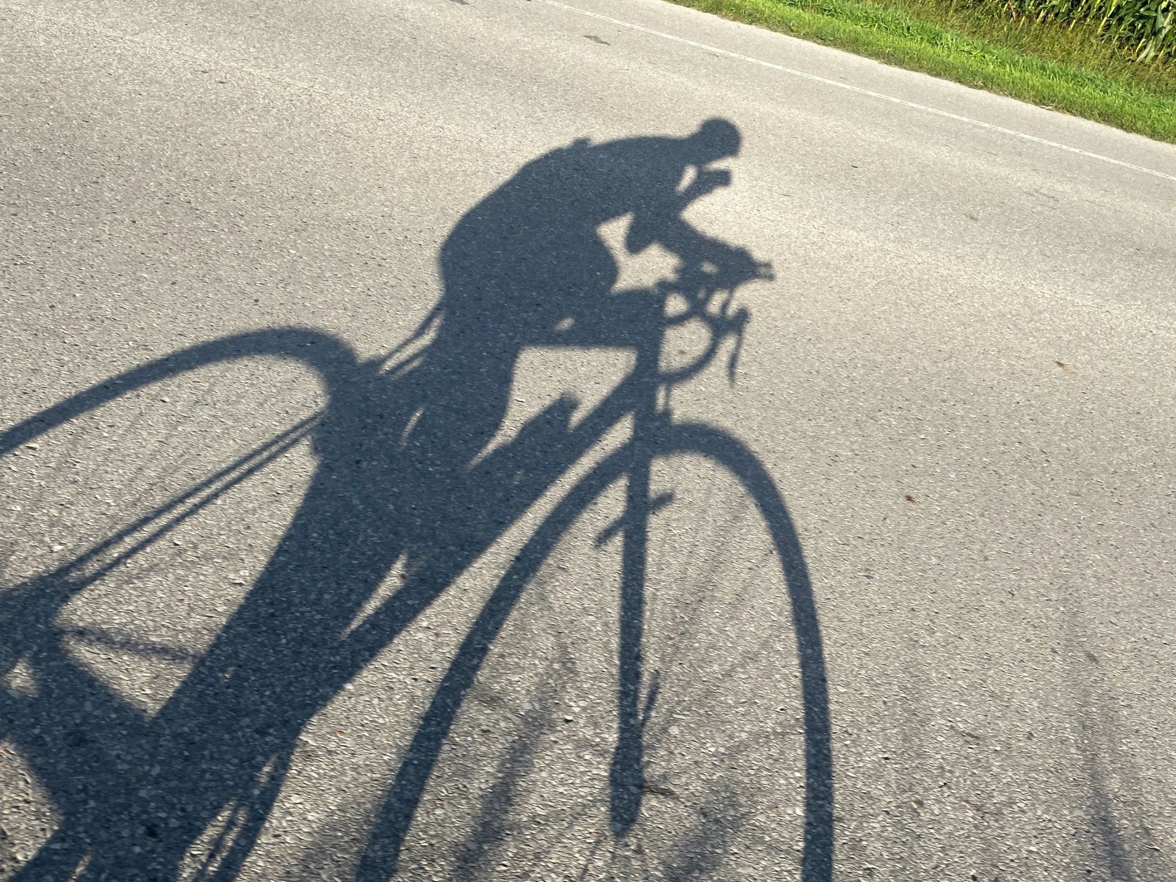 Long shadow of a cyclist cast on the pavement