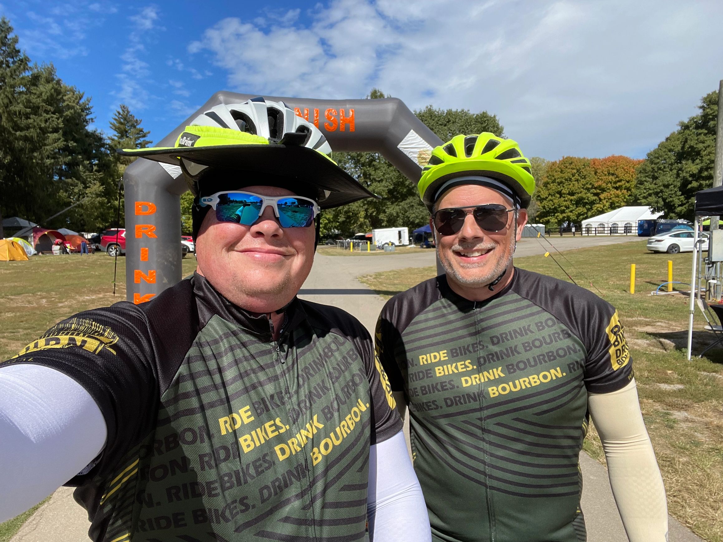 Two riders in Ride Bikes Drink Bourbon jerseys at the finish arch