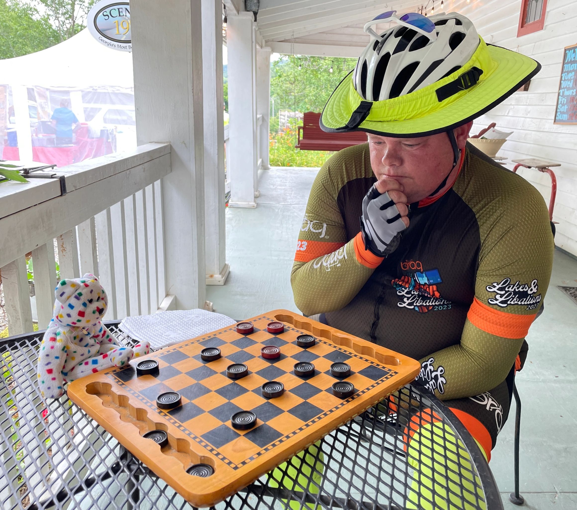 Rider playing checkers on a porch in a Lakes and Libations 2023 jersey