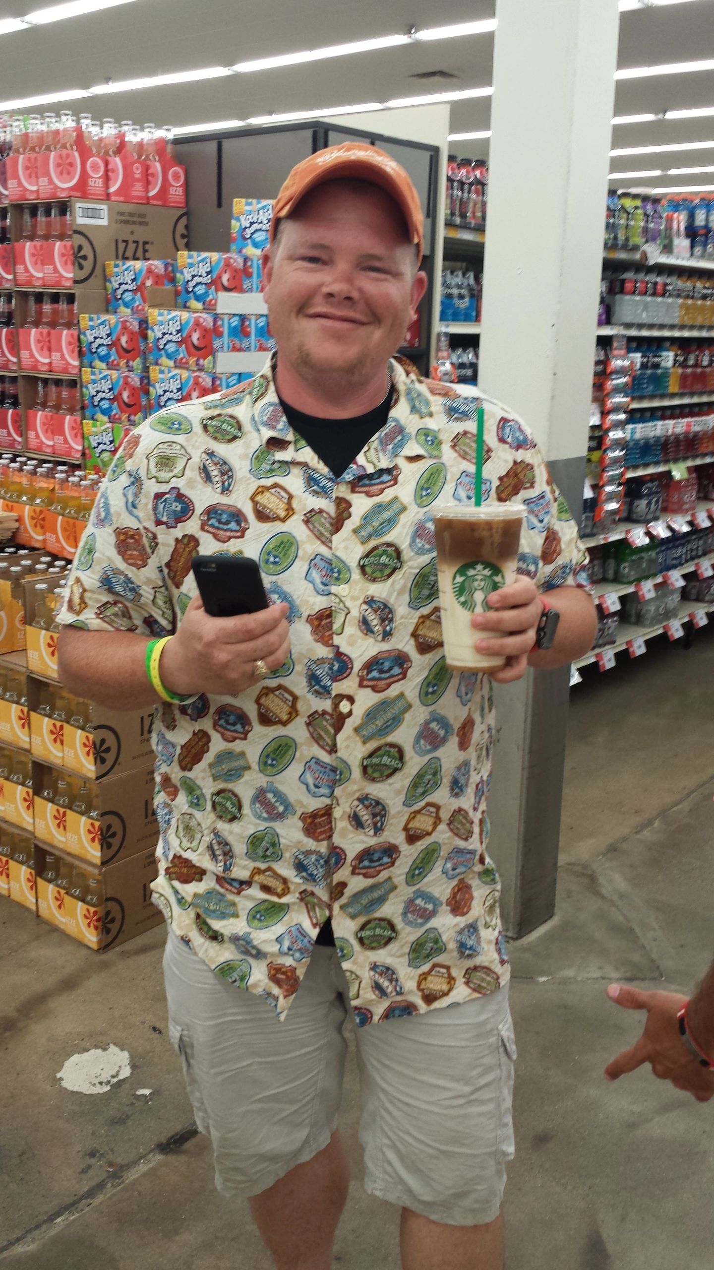 Rider in a stamp-print shirt with an iced coffee at a convenience store