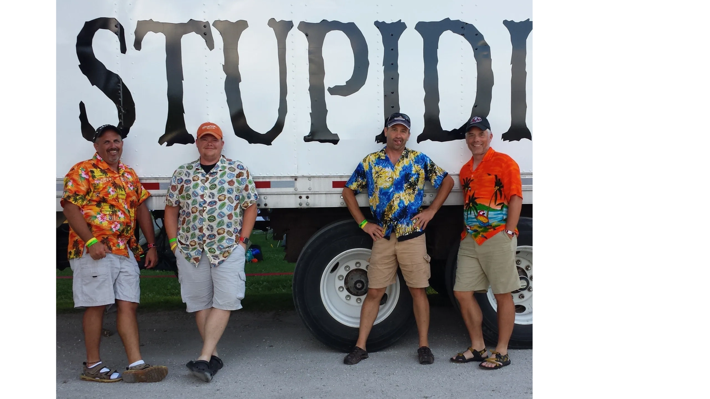 Four riders in Hawaiian shirts by a support truck